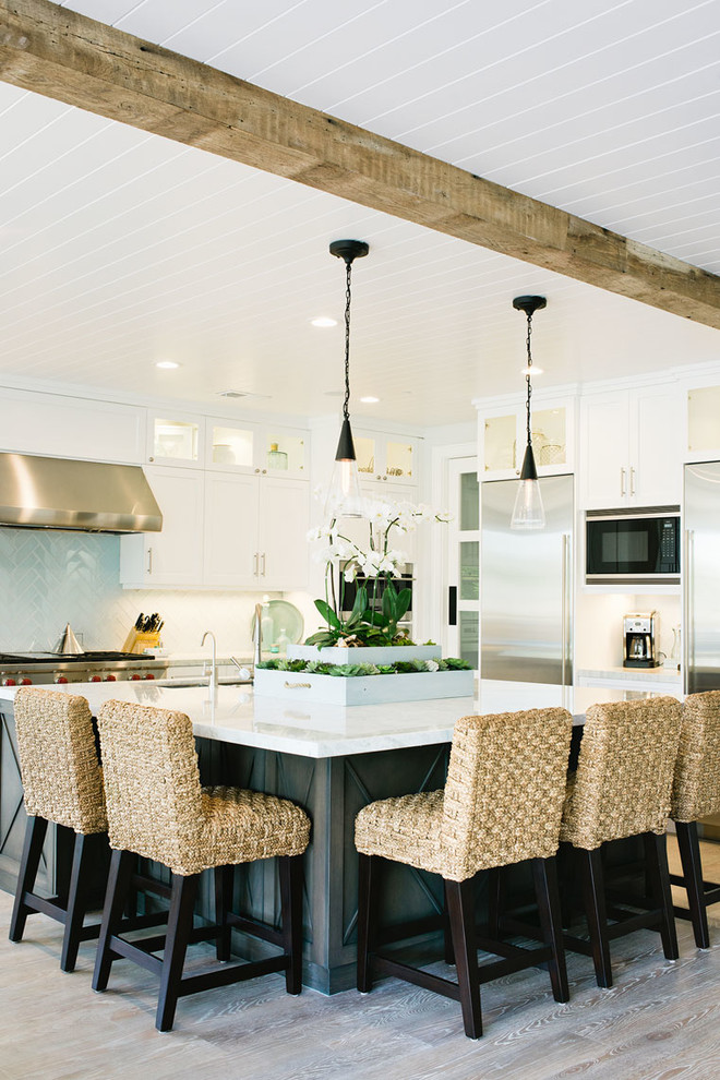 Inspiration for a coastal light wood floor kitchen remodel in Los Angeles with shaker cabinets, white cabinets, white backsplash, ceramic backsplash, stainless steel appliances and an island