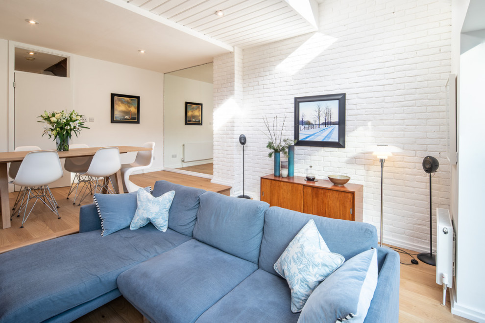 Idée de décoration pour un salon nordique ouvert avec un mur blanc, un sol en bois brun, un poêle à bois, un plafond en lambris de bois et un mur en parement de brique.