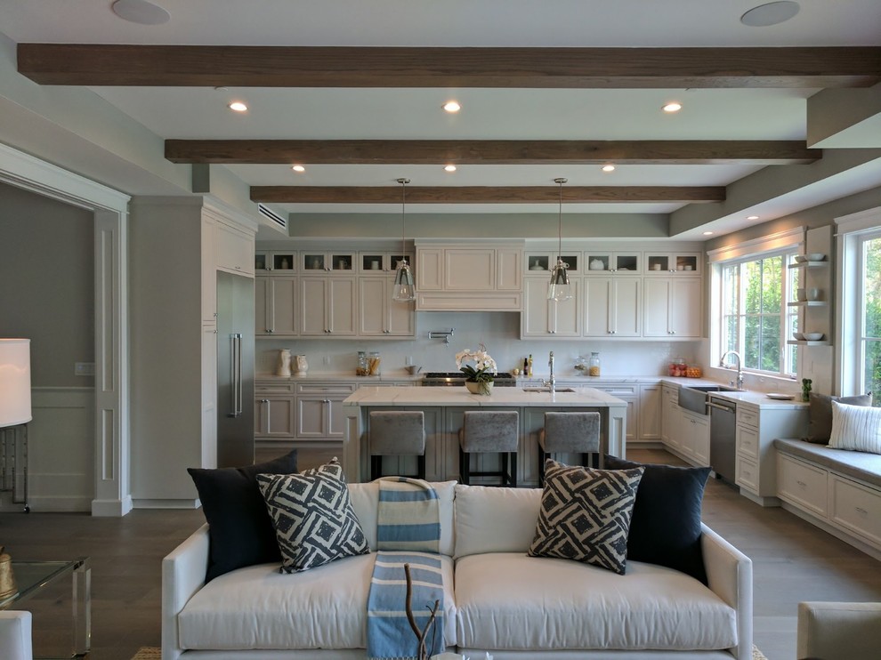 This is an example of a large beach style u-shaped eat-in kitchen in Orange County with an undermount sink, recessed-panel cabinets, white cabinets, quartz benchtops, white splashback, stone slab splashback, stainless steel appliances, porcelain floors, with island, grey floor, white benchtop and exposed beam.