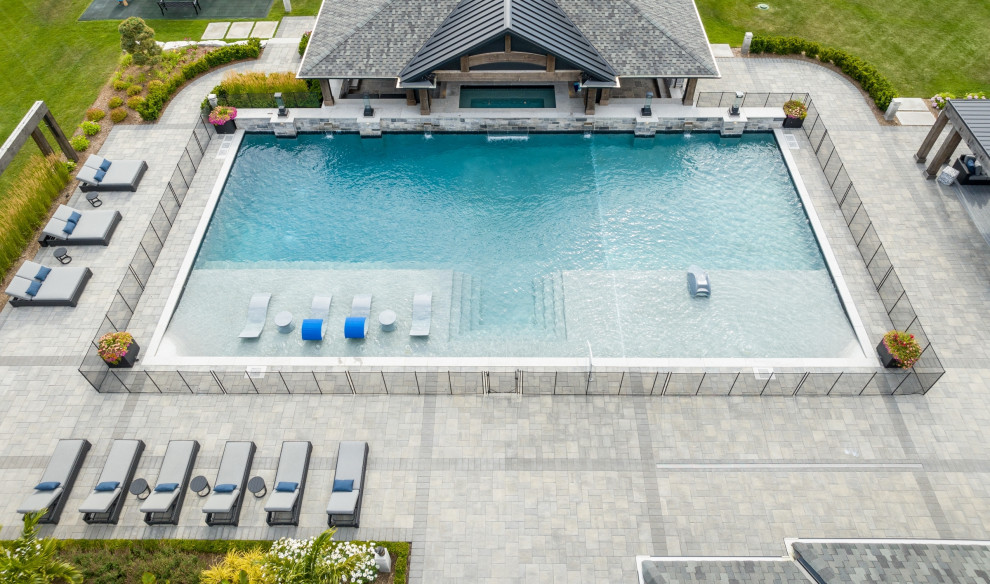 Cette image montre un très grand piscine avec aménagement paysager arrière traditionnel rectangle avec des pavés en béton.