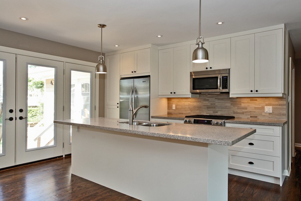 Inspiration for a mid-sized transitional single-wall medium tone wood floor eat-in kitchen remodel in Toronto with a double-bowl sink, shaker cabinets, white cabinets, granite countertops, beige backsplash, stone tile backsplash, stainless steel appliances and an island