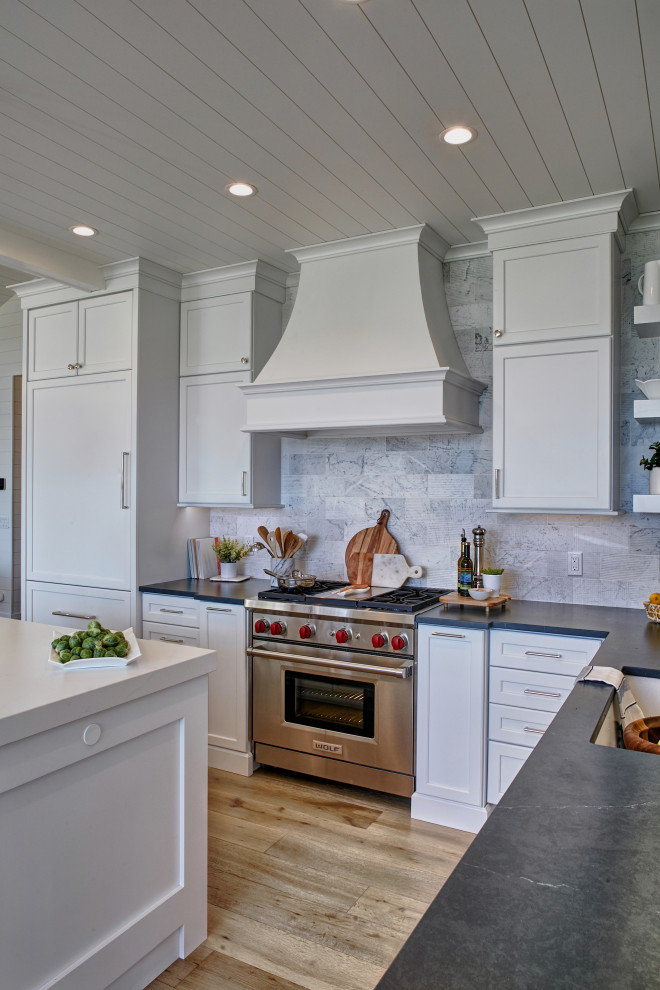 Photo of a mid-sized beach style l-shaped eat-in kitchen in Other with an undermount sink, flat-panel cabinets, white cabinets, quartzite benchtops, grey splashback, marble splashback, panelled appliances, light hardwood floors, with island, multi-coloured floor, blue benchtop and timber.