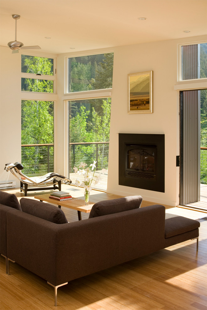 Photo of a mid-sized contemporary open concept living room in Other with white walls, bamboo floors, a standard fireplace, a metal fireplace surround and brown floor.
