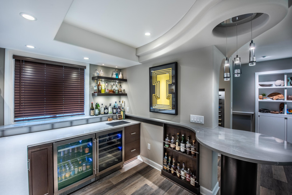 Design ideas for a mid-sized contemporary u-shaped wet bar in Other with an undermount sink, flat-panel cabinets, brown cabinets, quartzite benchtops, grey splashback, ceramic splashback, vinyl floors, brown floor and grey benchtop.