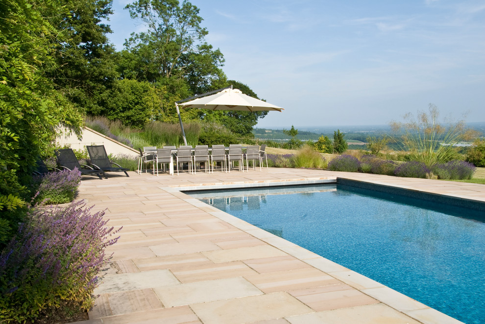 Design ideas for a large contemporary backyard rectangular lap pool in Sussex with natural stone pavers.
