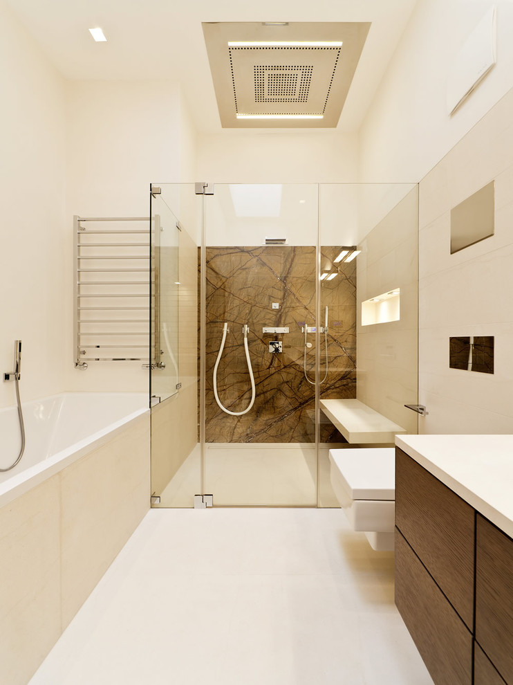Inspiration for a contemporary master bathroom in Hampshire with flat-panel cabinets, dark wood cabinets, a drop-in tub, a curbless shower, a wall-mount toilet, beige walls and a hinged shower door.