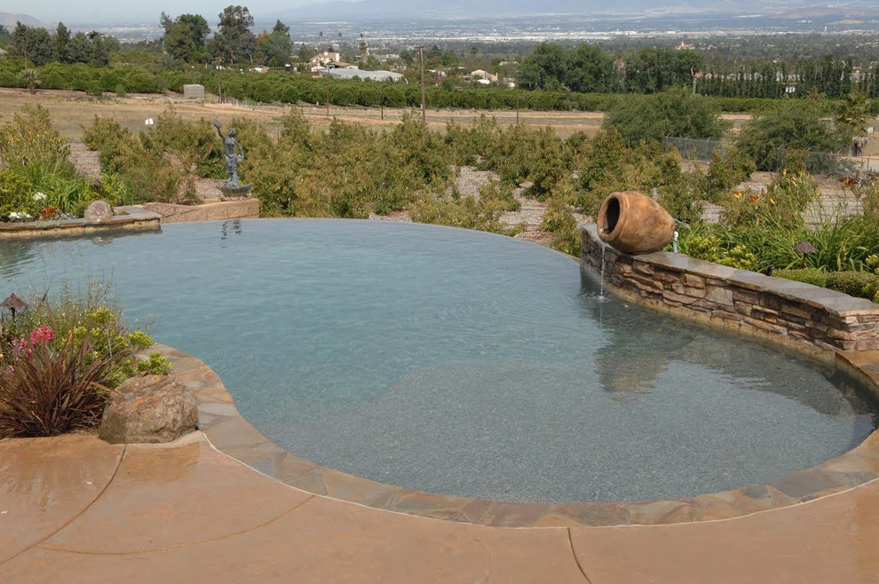 Example of a mid-sized transitional backyard concrete paver and custom-shaped lap hot tub design in Los Angeles