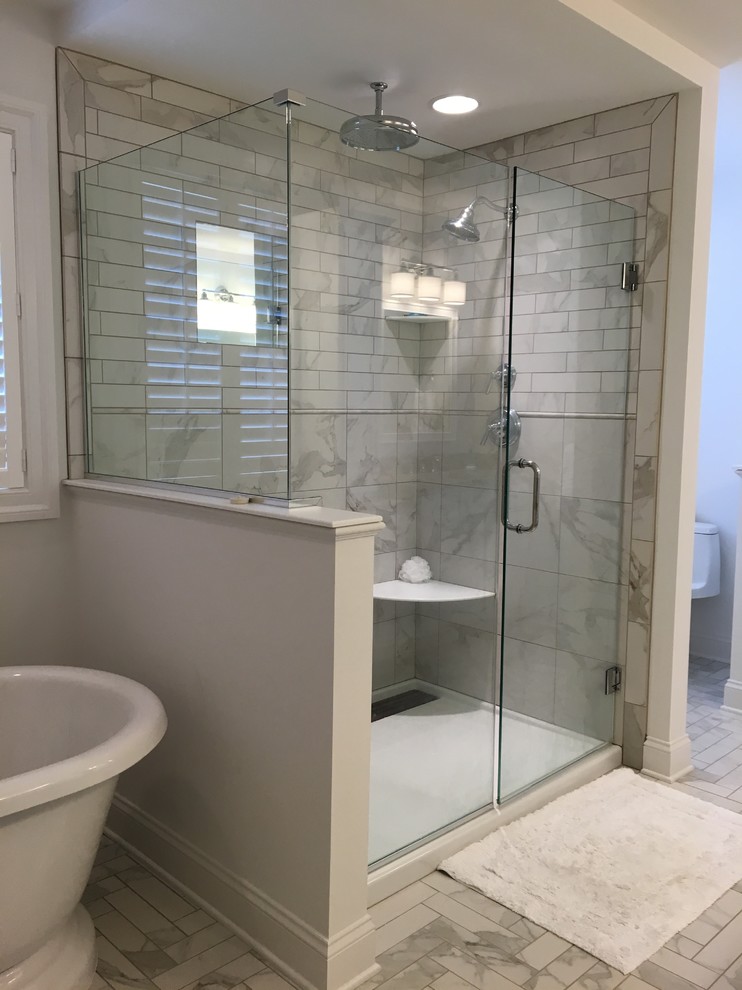 Photo of a large transitional master bathroom in Other with shaker cabinets, white cabinets, a freestanding tub, an alcove shower, a one-piece toilet, white tile, porcelain tile, white walls, porcelain floors, an undermount sink, engineered quartz benchtops, white floor, a hinged shower door and white benchtops.