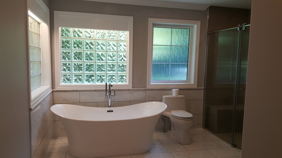 Inspiration for a mid-sized transitional freestanding bathtub remodel with a two-piece toilet, beige walls and a hinged shower door