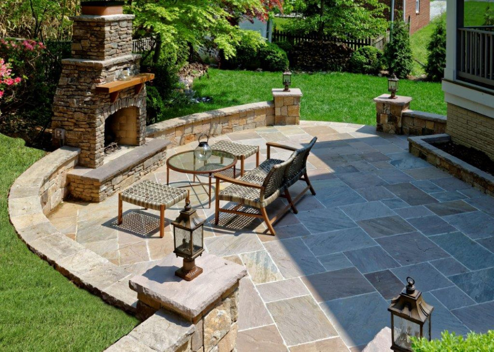 Immagine di un patio o portico mediterraneo di medie dimensioni e dietro casa con un caminetto, pavimentazioni in pietra naturale e nessuna copertura