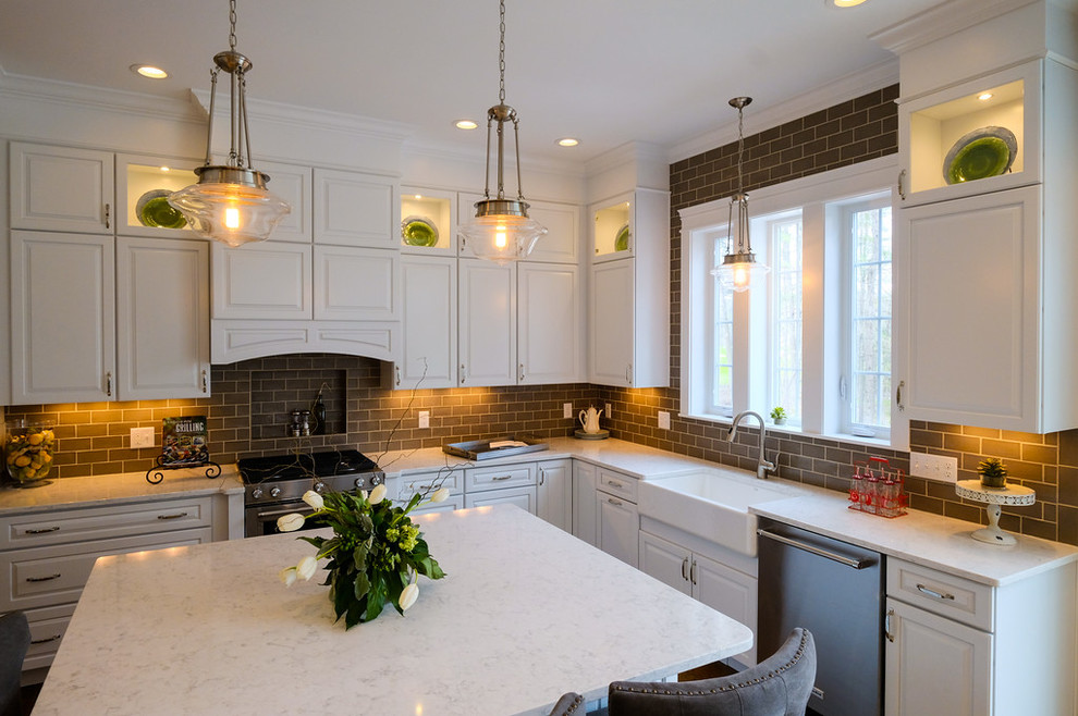 Mid-sized transitional u-shaped eat-in kitchen photo with a farmhouse sink, quartz countertops, brown backsplash, stainless steel appliances, an island and white cabinets
