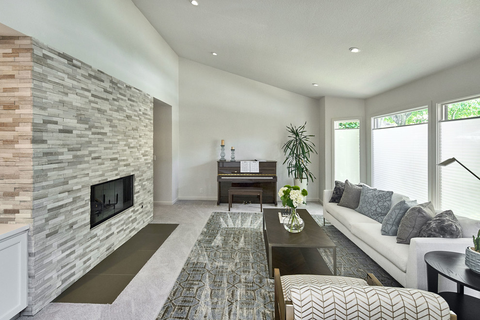 This is an example of a mid-sized transitional enclosed living room in San Francisco with a music area, carpet, a standard fireplace, a stone fireplace surround, beige floor and white walls.