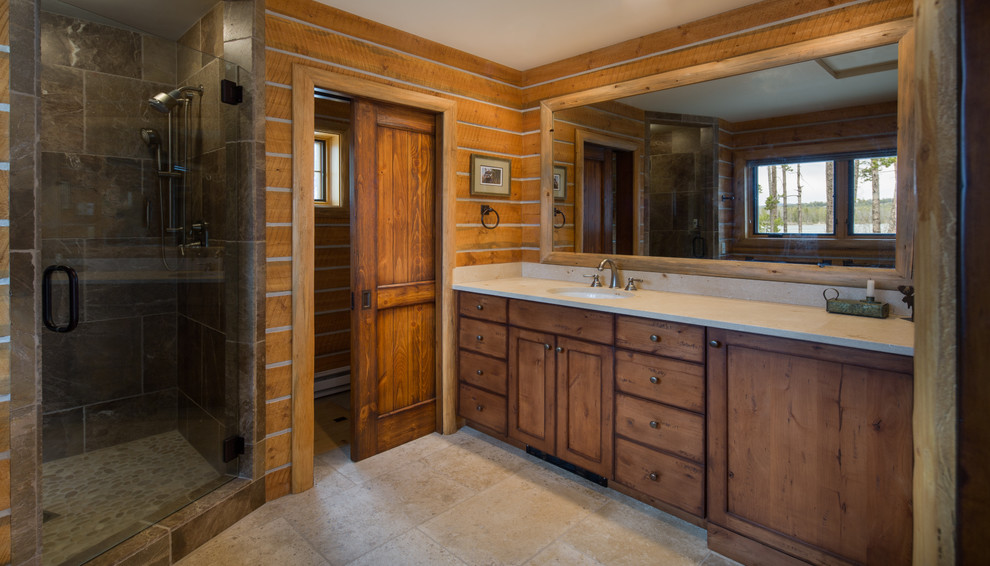 Photo of a mid-sized country master bathroom in Boise with recessed-panel cabinets, distressed cabinets, a corner shower, beige tile, an undermount sink and a hinged shower door.