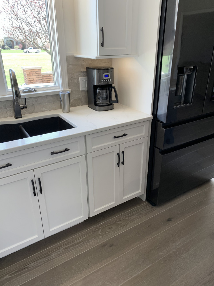 Eat-in kitchen - large transitional l-shaped vinyl floor and gray floor eat-in kitchen idea with an undermount sink, recessed-panel cabinets, white cabinets, quartz countertops, gray backsplash, ceramic backsplash, stainless steel appliances, an island and white countertops