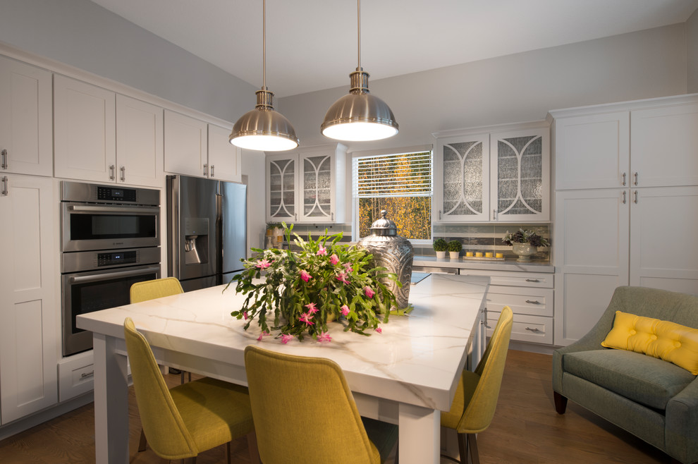 Inspiration for a transitional l-shaped light wood floor and gray floor open concept kitchen remodel in Denver with an undermount sink, shaker cabinets, white cabinets, quartz countertops, multicolored backsplash, glass tile backsplash, stainless steel appliances, an island and white countertops