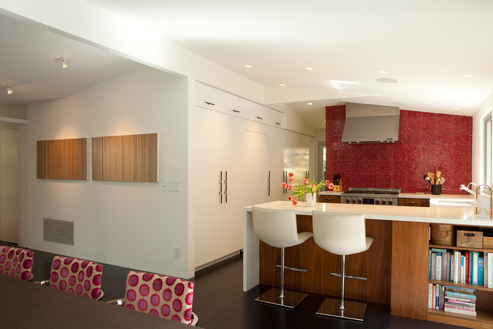 This is an example of a large midcentury u-shaped eat-in kitchen in Los Angeles with an undermount sink, flat-panel cabinets, medium wood cabinets, red splashback, mosaic tile splashback, stainless steel appliances, dark hardwood floors, a peninsula, brown floor and white benchtop.