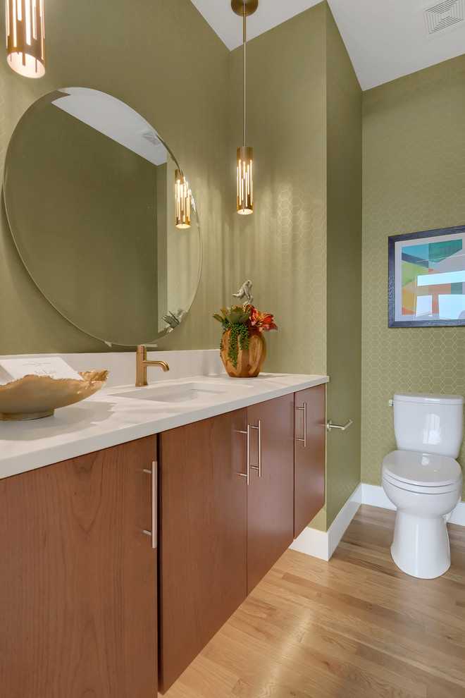 Mid-sized contemporary powder room in Denver with flat-panel cabinets, medium wood cabinets, a two-piece toilet, green walls, light hardwood floors, an undermount sink, engineered quartz benchtops, white benchtops and beige floor.