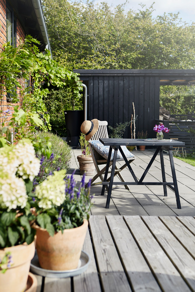 This is an example of a mid-sized country patio in Aarhus with decking and no cover.