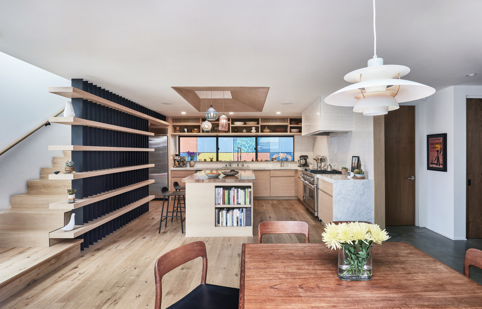 Photo of a large scandinavian u-shaped open plan kitchen in Los Angeles with a double-bowl sink, raised-panel cabinets, light wood cabinets, marble benchtops, white splashback, ceramic splashback, stainless steel appliances, light hardwood floors, with island, beige floor and white benchtop.