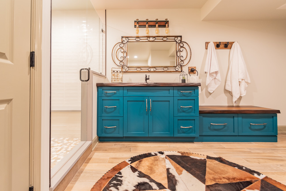 Design ideas for a mid-sized country 3/4 bathroom in Philadelphia with shaker cabinets, turquoise cabinets, an alcove shower, a one-piece toilet, beige tile, beige walls, porcelain floors, a console sink, concrete benchtops, brown floor, a hinged shower door and brown benchtops.