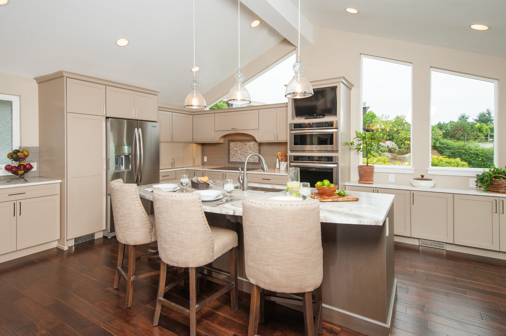 Inspiration for a transitional l-shaped medium tone wood floor and brown floor open concept kitchen remodel in Seattle with shaker cabinets, beige cabinets, beige backsplash, stainless steel appliances, an undermount sink, quartzite countertops, subway tile backsplash and an island