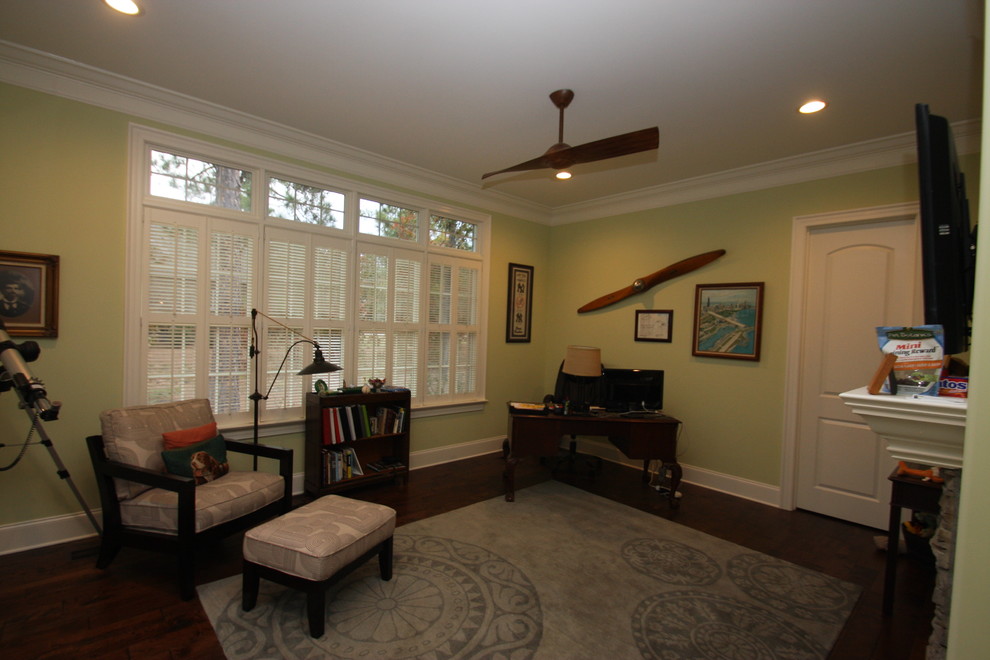 Mid-sized traditional home office in Raleigh with green walls, dark hardwood floors, a freestanding desk, brown floor, a standard fireplace and a stone fireplace surround.
