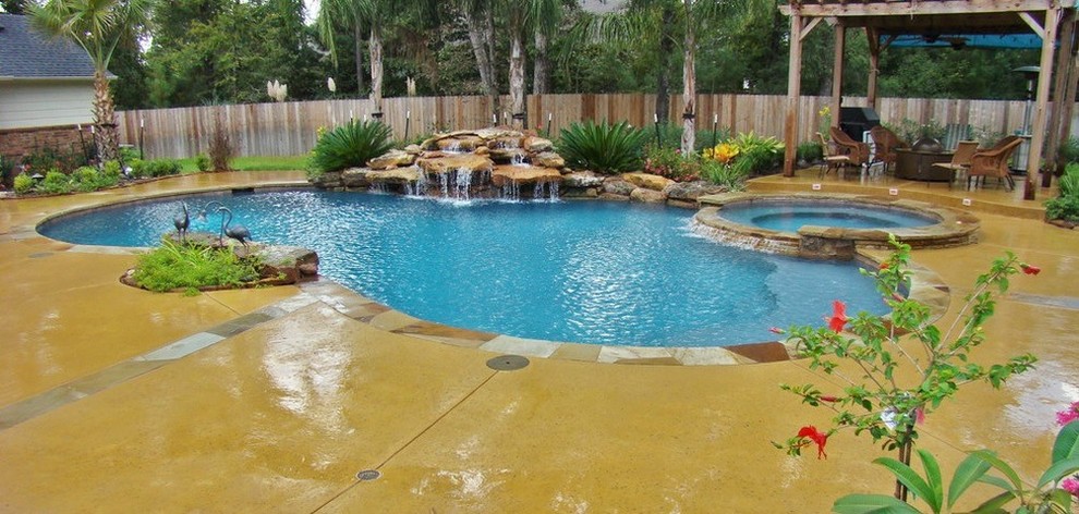 Design ideas for a large modern backyard custom-shaped pool in Houston with a water feature and stamped concrete.