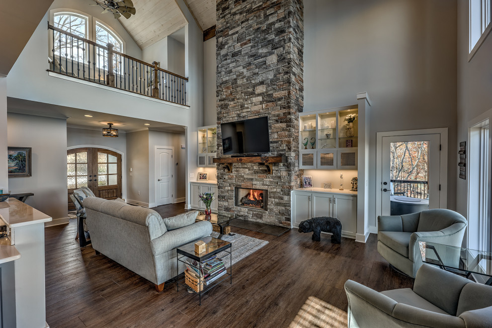 Inspiration for a large craftsman formal and open concept vinyl floor, brown floor and vaulted ceiling living room remodel in Atlanta with beige walls, a standard fireplace, a stone fireplace and a wall-mounted tv