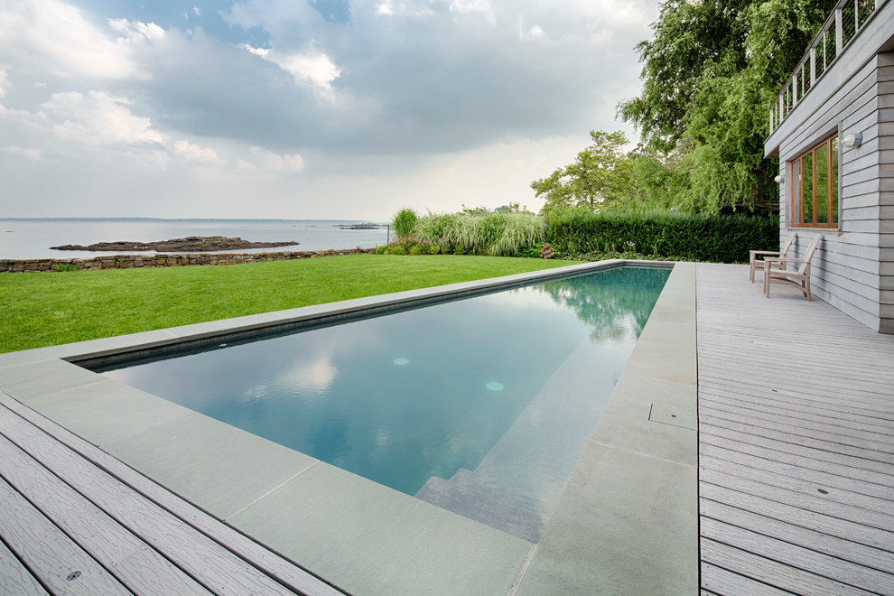 Design ideas for a large contemporary backyard custom-shaped lap pool in New York with decking.