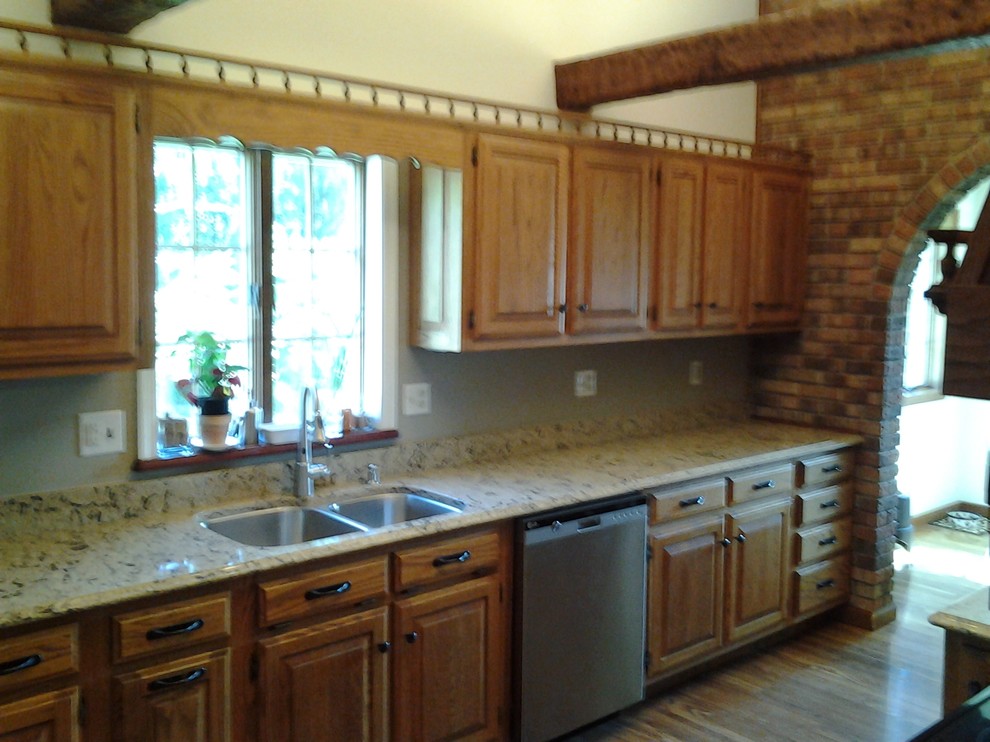 Inspiration for a mid-sized rustic medium tone wood floor enclosed kitchen remodel in Indianapolis with an undermount sink, raised-panel cabinets, medium tone wood cabinets, quartzite countertops, stainless steel appliances and no island