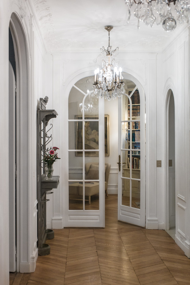 This is an example of a transitional hallway in Paris with white walls, medium hardwood floors and beige floor.