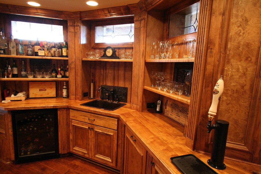 Photo of a large country u-shaped seated home bar in Atlanta with a drop-in sink, medium wood cabinets, wood benchtops, brown splashback, timber splashback, medium hardwood floors and brown floor.