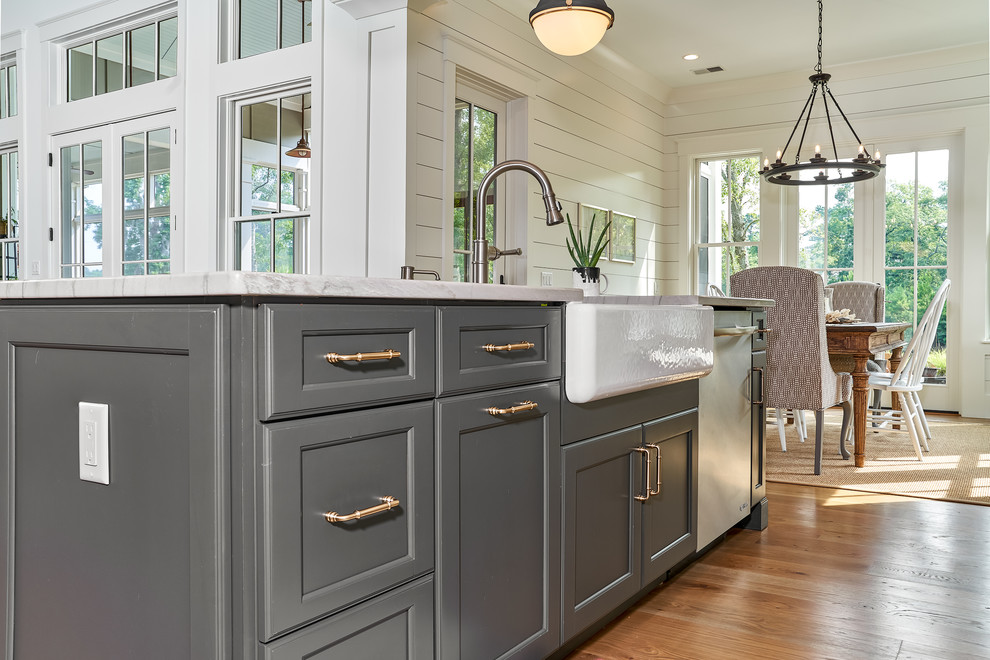 Inspiration for a mid-sized beach style u-shaped eat-in kitchen in Charleston with a farmhouse sink, shaker cabinets, beige cabinets, quartzite benchtops, white splashback, timber splashback, stainless steel appliances, light hardwood floors, with island, brown floor and multi-coloured benchtop.