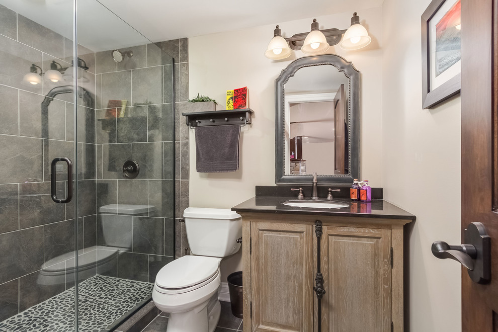 Inspiration for a small transitional bathroom in Chicago with furniture-like cabinets, light wood cabinets, an alcove shower, a two-piece toilet, gray tile, slate, beige walls, porcelain floors, an undermount sink, granite benchtops, grey floor, a hinged shower door and grey benchtops.
