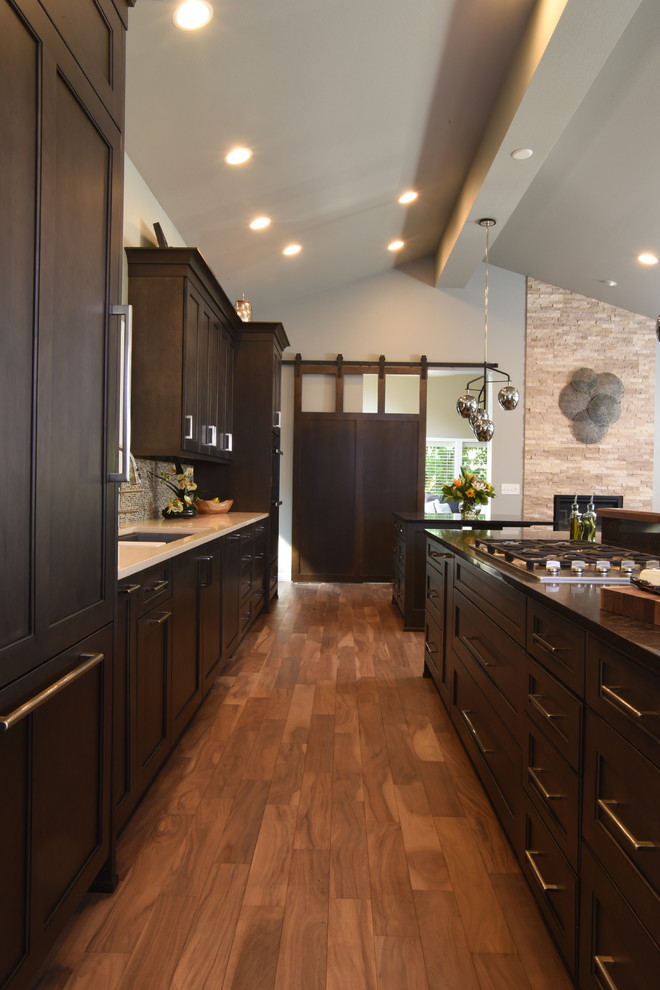 Example of a transitional galley medium tone wood floor kitchen design in Seattle with shaker cabinets, dark wood cabinets, quartzite countertops and two islands
