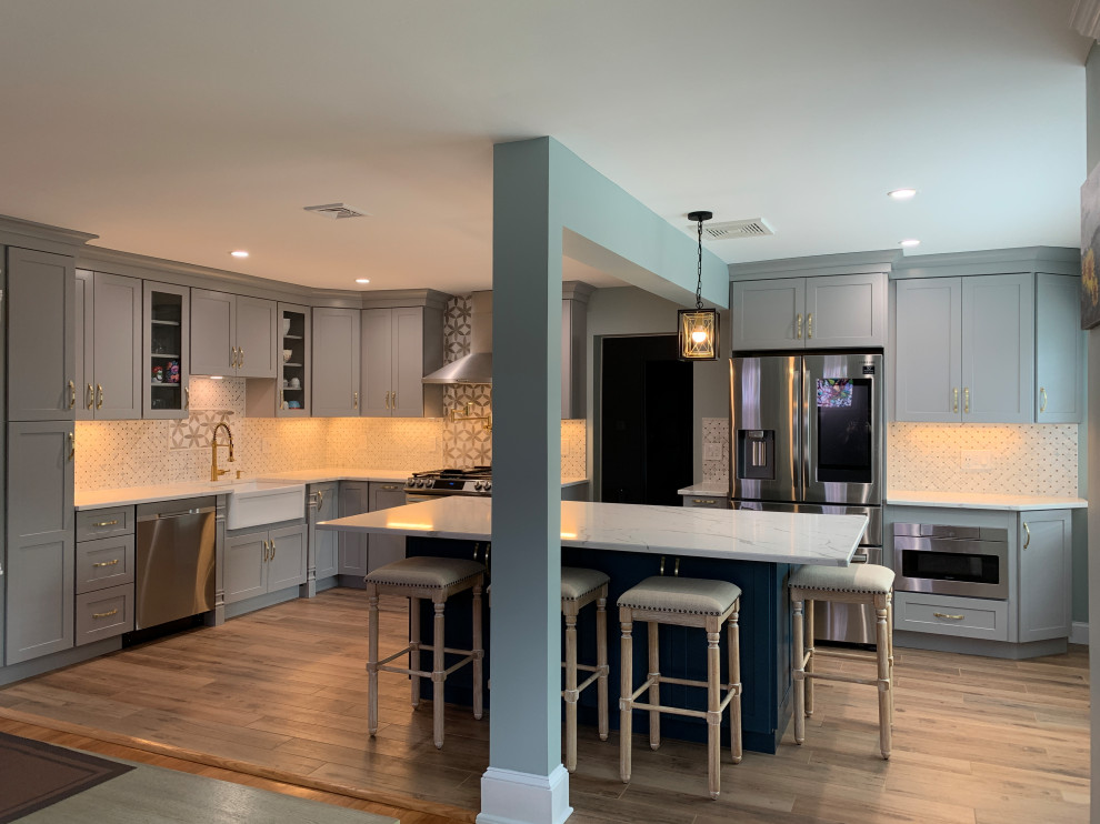 Example of a large minimalist l-shaped porcelain tile and gray floor eat-in kitchen design in Newark with a farmhouse sink, shaker cabinets, gray cabinets, quartzite countertops, multicolored backsplash, mosaic tile backsplash, stainless steel appliances, an island and white countertops