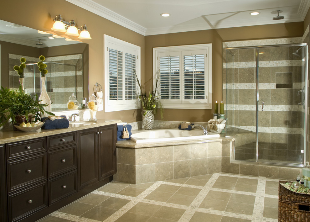 Large tropical master bathroom in Jacksonville with dark wood cabinets, a corner shower, a one-piece toilet, beige tile, ceramic tile, pebble tile floors, an undermount sink, marble benchtops, multi-coloured floor, a hinged shower door, beaded inset cabinets, a corner tub, beige walls and beige benchtops.