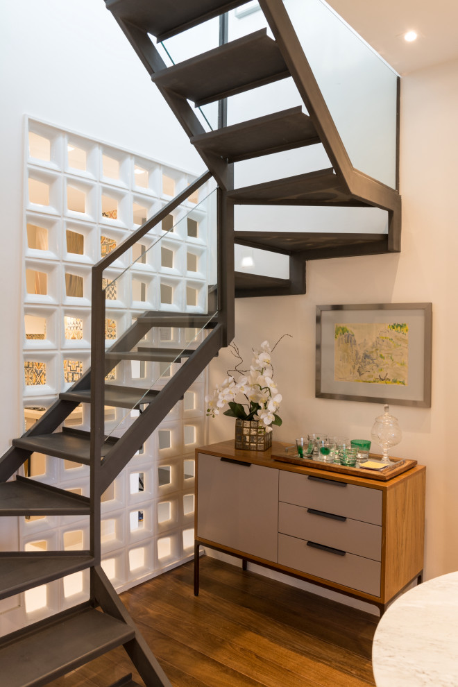 Ejemplo de escalera en L contemporánea pequeña con escalones de metal, barandilla de vidrio y ladrillo