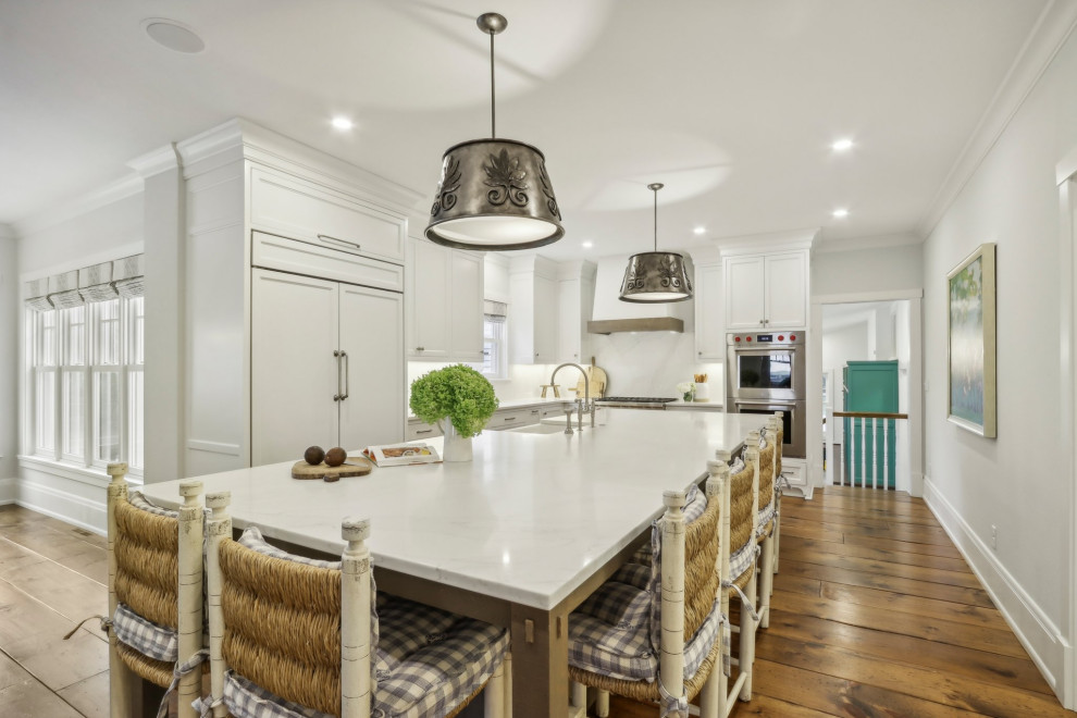 Inspiration for a mid-sized rustic l-shaped medium tone wood floor and brown floor eat-in kitchen remodel in Milwaukee with a farmhouse sink, shaker cabinets, white cabinets, quartz countertops, white backsplash, quartz backsplash, stainless steel appliances, an island and multicolored countertops