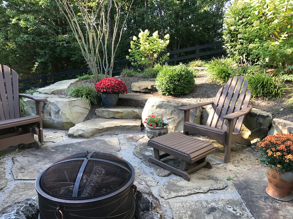 Example of a mid-sized mountain style backyard stone patio design with a fire pit and no cover