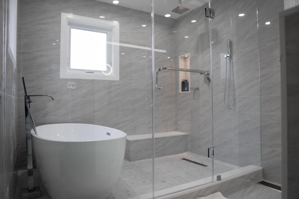 Exempel på ett mellanstort modernt vit vitt en-suite badrum, med skåp i shakerstil, vita skåp, ett fristående badkar, en kantlös dusch, en toalettstol med hel cisternkåpa, grå kakel, porslinskakel, grå väggar, klinkergolv i porslin, ett undermonterad handfat, bänkskiva i kvarts, grått golv och dusch med skjutdörr