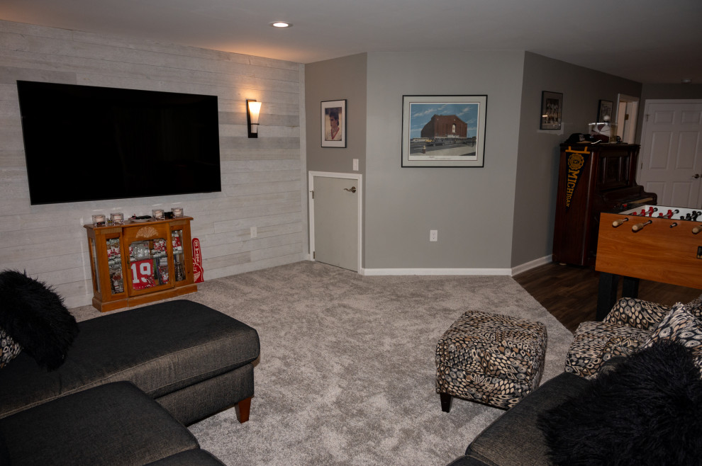 Mittelgroßes, Offenes Klassisches Wohnzimmer mit Teppichboden, TV-Wand, braunem Boden und Holzwänden in Detroit