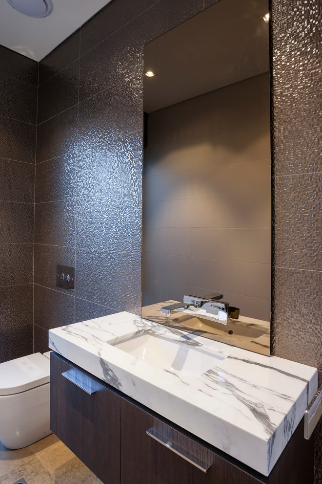 This is an example of a mid-sized contemporary powder room in Perth with an undermount sink, flat-panel cabinets, dark wood cabinets, marble benchtops, a one-piece toilet, ceramic tile and limestone floors.