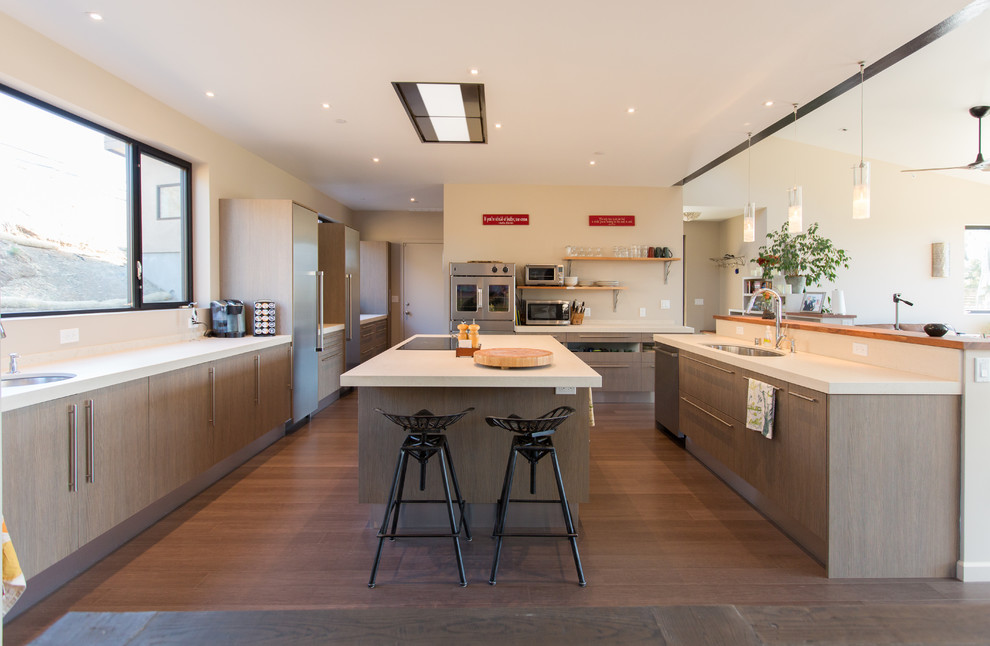 This is an example of a large contemporary eat-in kitchen in San Francisco with a drop-in sink, flat-panel cabinets, medium wood cabinets, stainless steel appliances and with island.