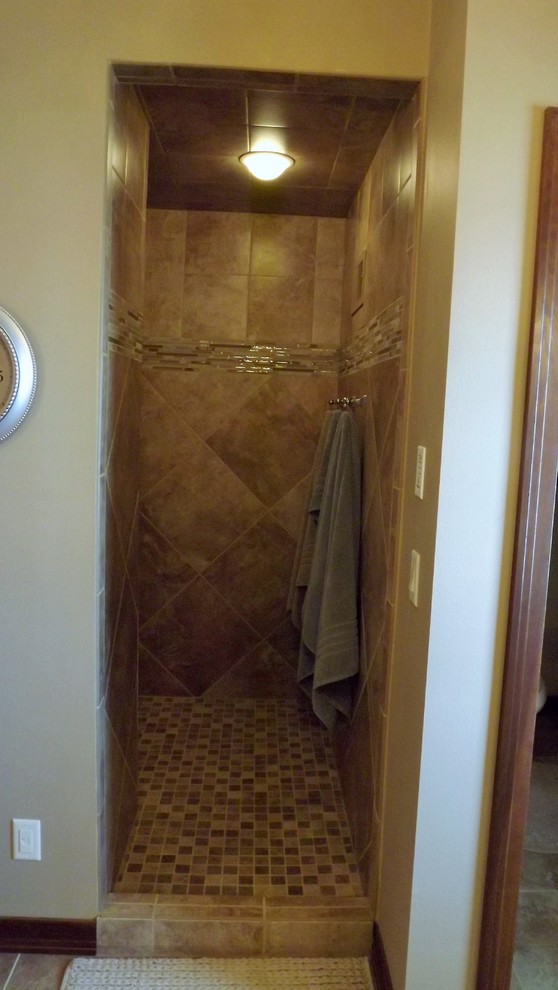 Transitional beige tile and porcelain tile porcelain tile doorless shower photo with an undermount sink, raised-panel cabinets, medium tone wood cabinets, granite countertops and beige walls