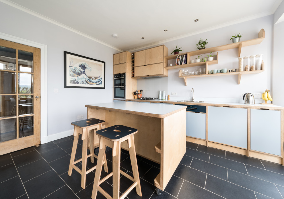 Mid-sized beach style single-wall eat-in kitchen in Edinburgh with a single-bowl sink, wood benchtops, white splashback, glass sheet splashback, stainless steel appliances, with island and grey benchtop.