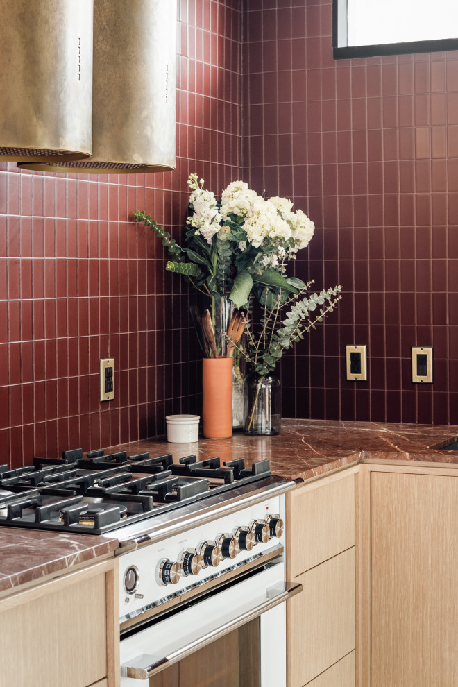 Exempel på ett mellanstort retro röd rött kök, med en integrerad diskho, släta luckor, skåp i ljust trä, marmorbänkskiva, rött stänkskydd, stänkskydd i glaskakel, vita vitvaror, terrazzogolv, en halv köksö och grått golv