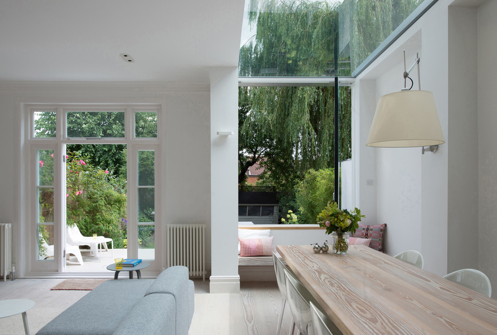 Photo of a mid-sized contemporary open plan dining in London with white walls, light hardwood floors and no fireplace.