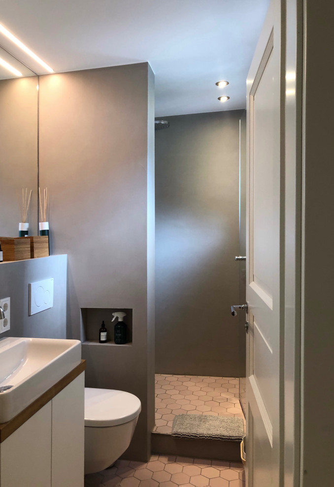Exempel på ett litet modernt vit vitt badrum med dusch, med släta luckor, vita skåp, en öppen dusch, en vägghängd toalettstol, beige väggar, mosaikgolv, ett fristående handfat, rosa golv och med dusch som är öppen