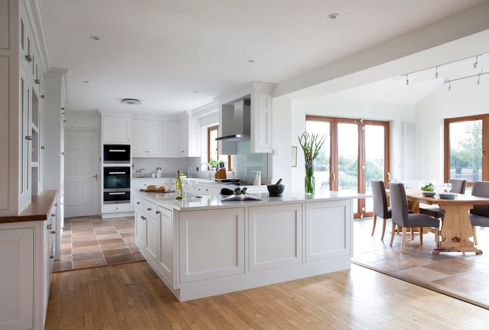 Design ideas for a transitional u-shaped eat-in kitchen in Dublin with an undermount sink, beaded inset cabinets, white cabinets, grey splashback, stone slab splashback and stainless steel appliances.